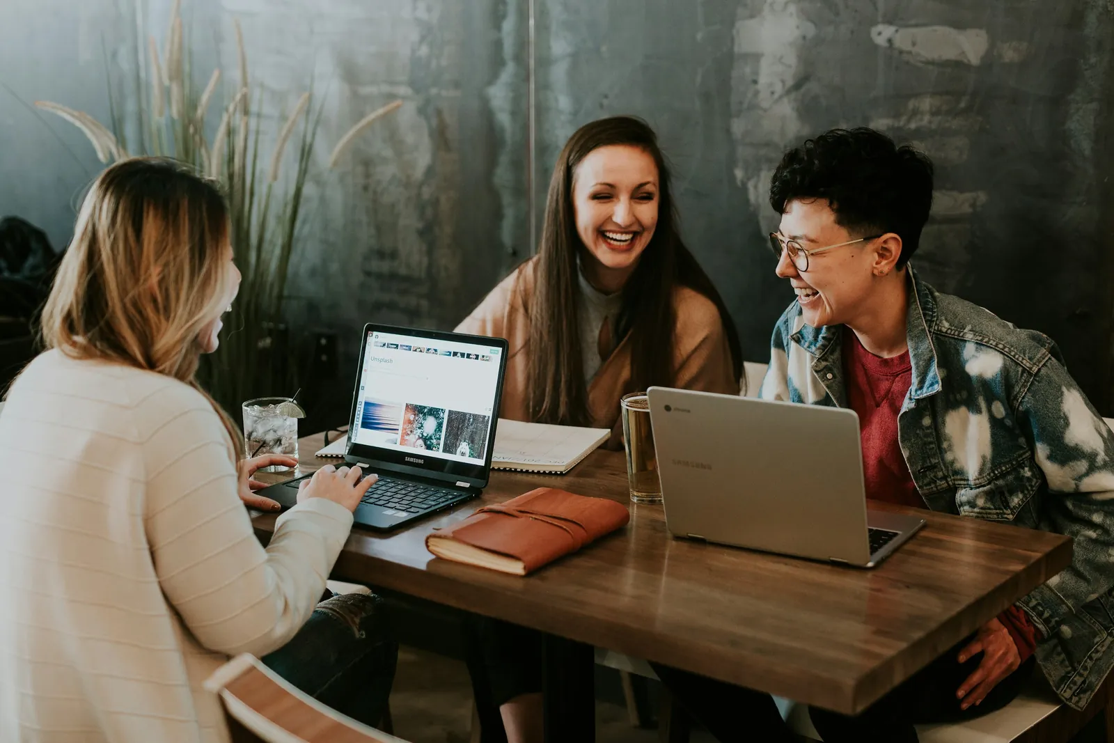 Drei Personen arbeiten gemeinsam an Inhalten an Laptops