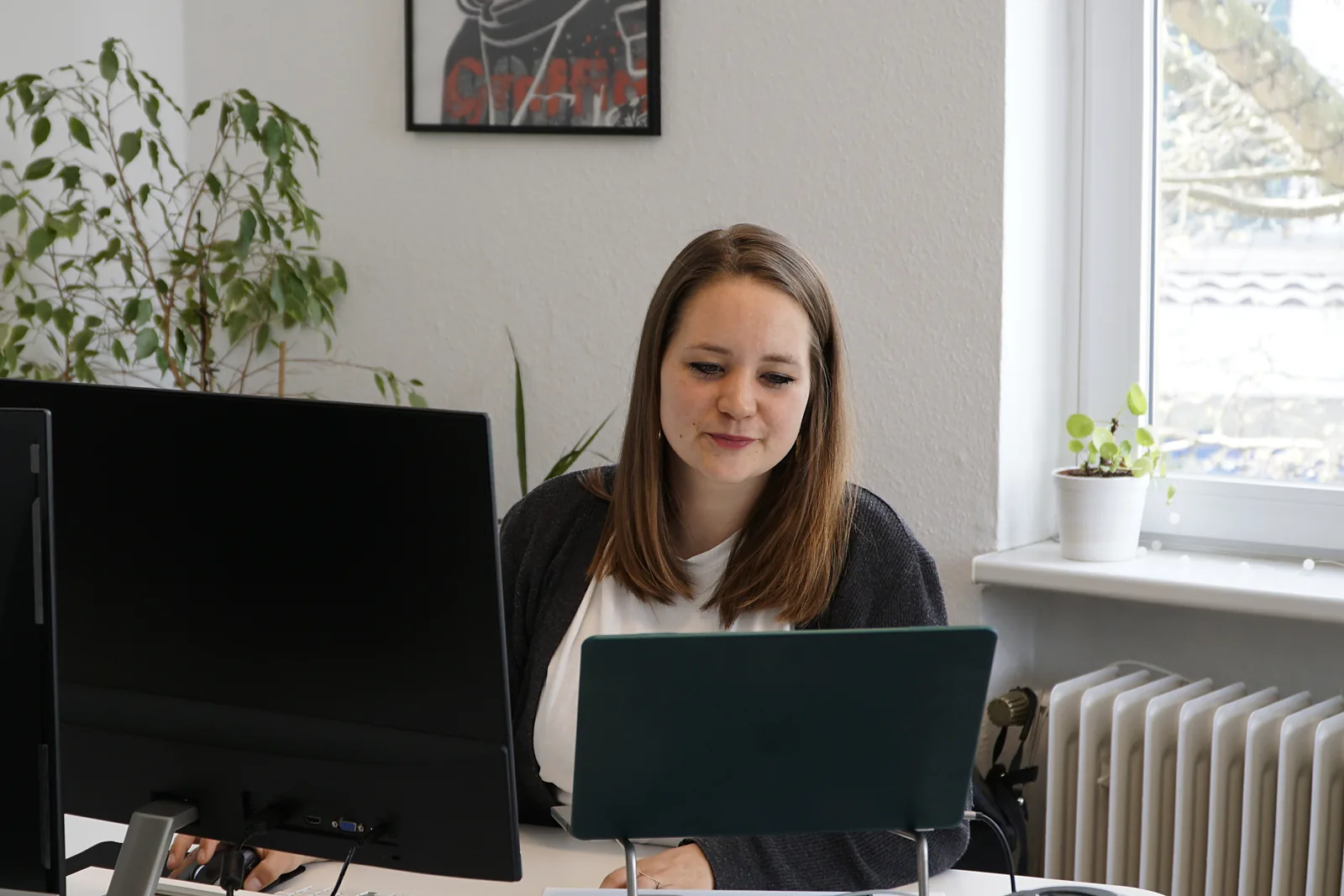 Eine Mitarbeiterin von EOM arbeitet im Büro in Hannover am Laptop, links stehen zwei Monitore