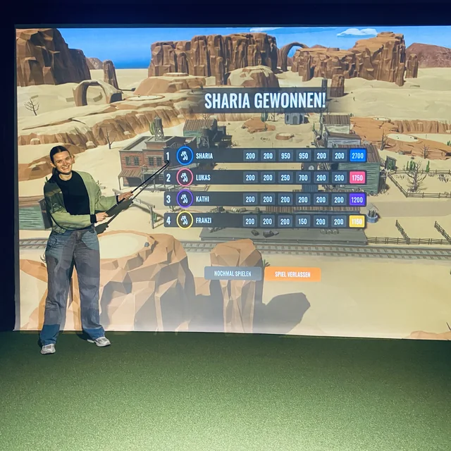 Eine Kollegin von EOM vor der Leinwand eines Golfsimulators, die ihren Sieg anzeigt
