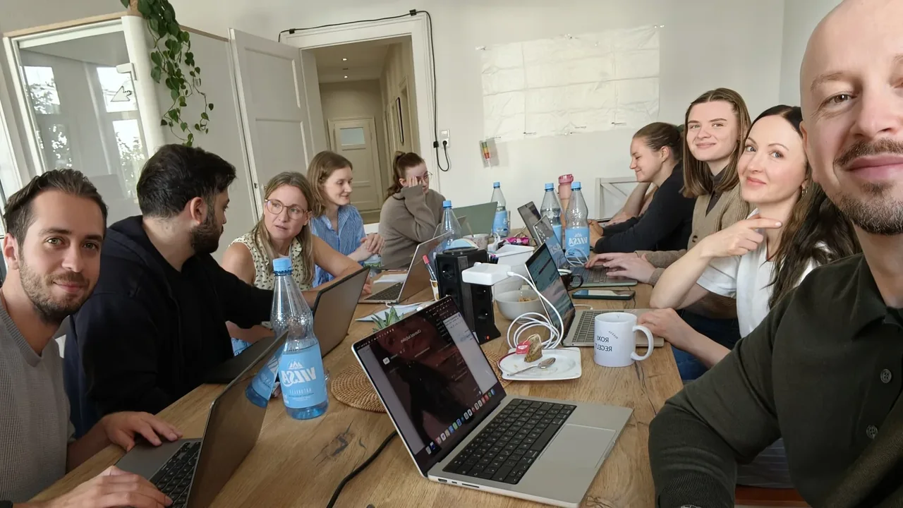 Das Team von EOM sitzt beim KI-Workshop mit Laptops an einem langen Tisch im Büro in Hannover