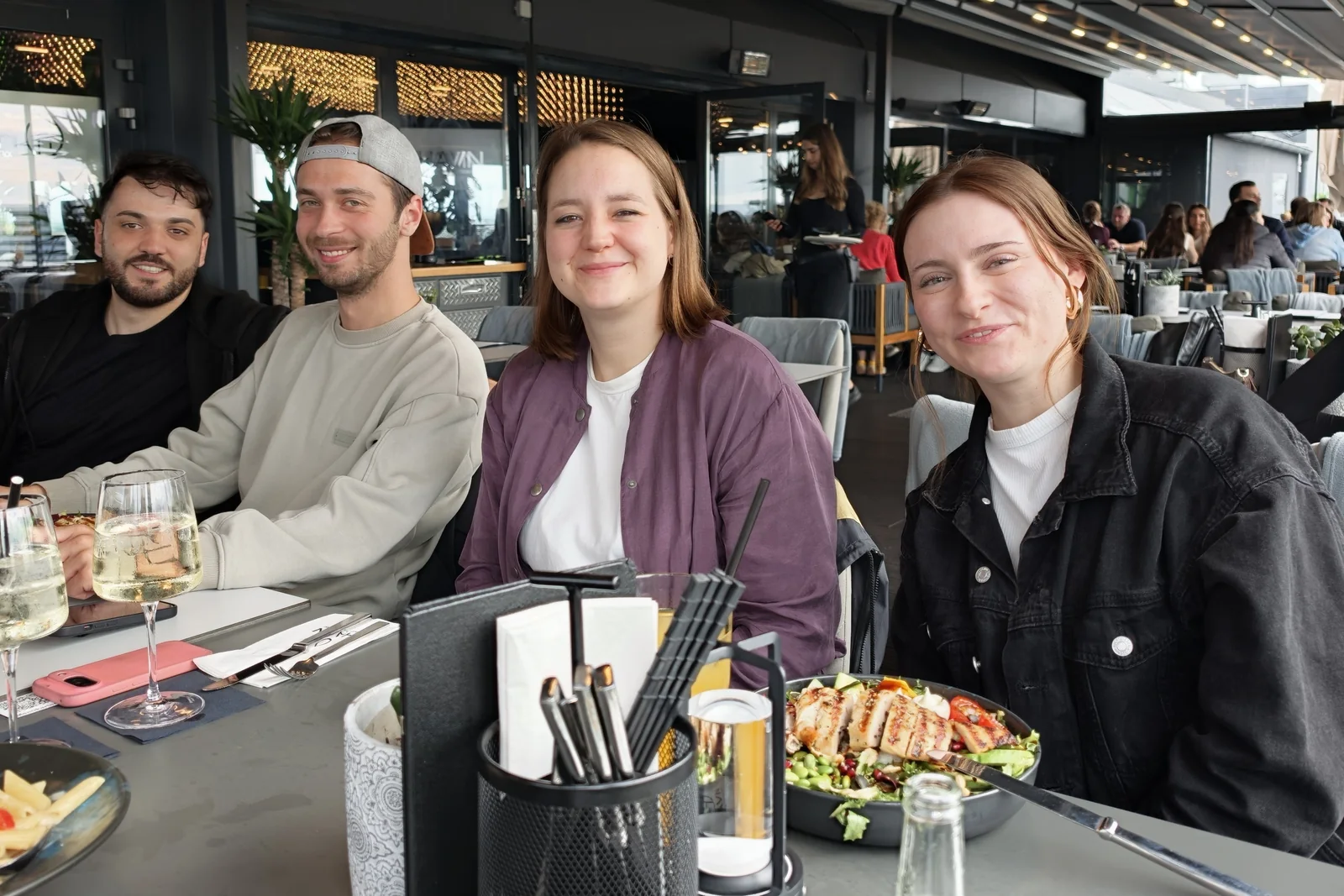 Vier aus dem Team von EOM sitzen lachend an einem Tisch auf einer Dachterrasse in Hannover