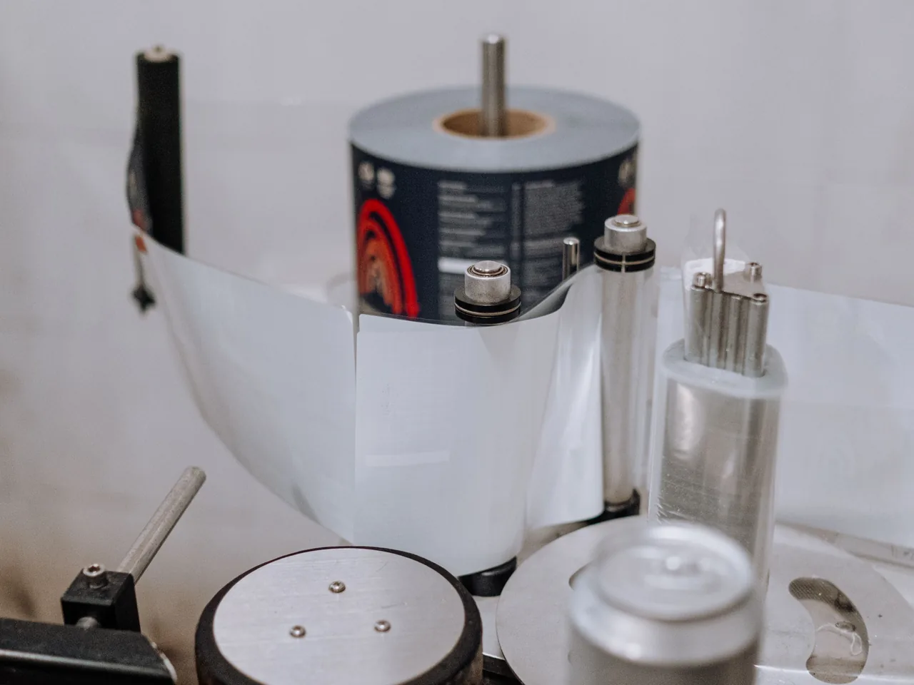 Rolle mit bedruckten Etiketten in einer Etikettiermaschine, das Trägerband läuft über die Umlenkrollen zu den Dosen