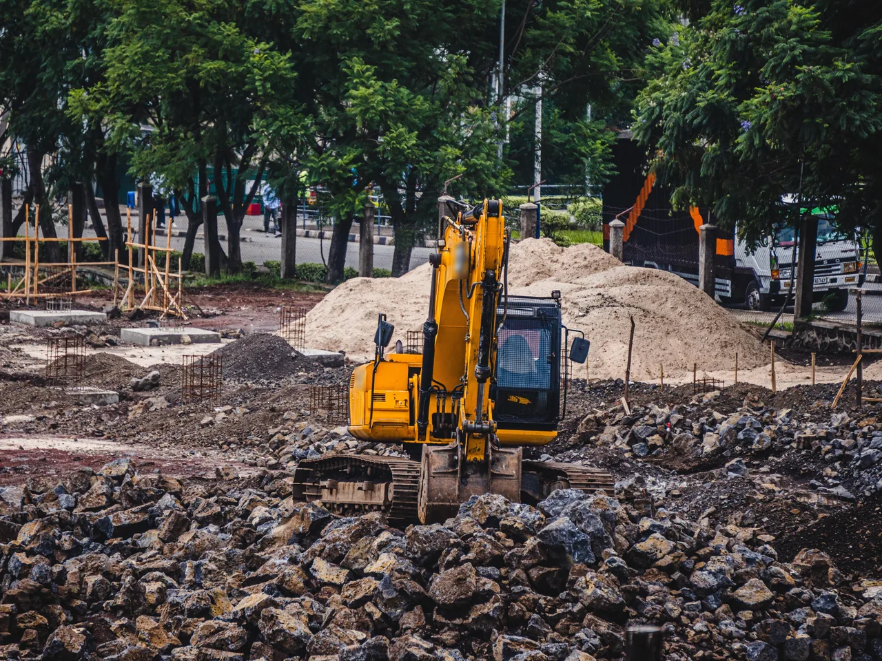 Gelber Kettenbagger auf einer Baustelle mit Schotter und Sandhaufen