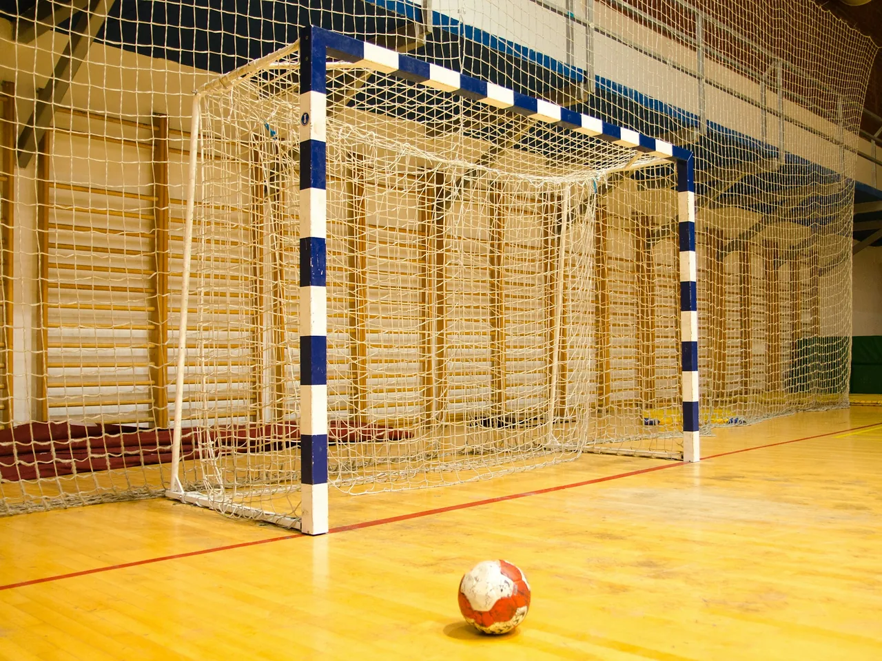 Handballtor in einer Sporthalle mit einem Ball auf dem Hallenboden