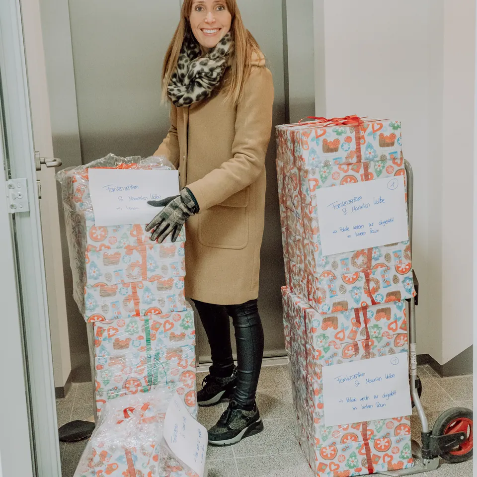 Das Team packt an einem Tisch mit grünem Geschenkband gemeinsam Geschenke ein, Dezember 2019