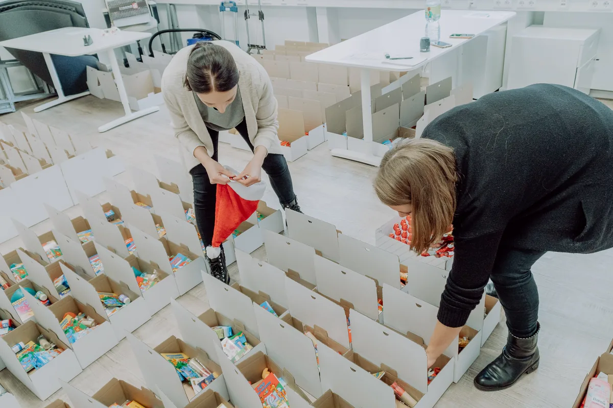 Zwei Kolleginnen füllen im Büro Reihen von Geschenkkartons für die Nikolaus-Aktion im Dezember 2019