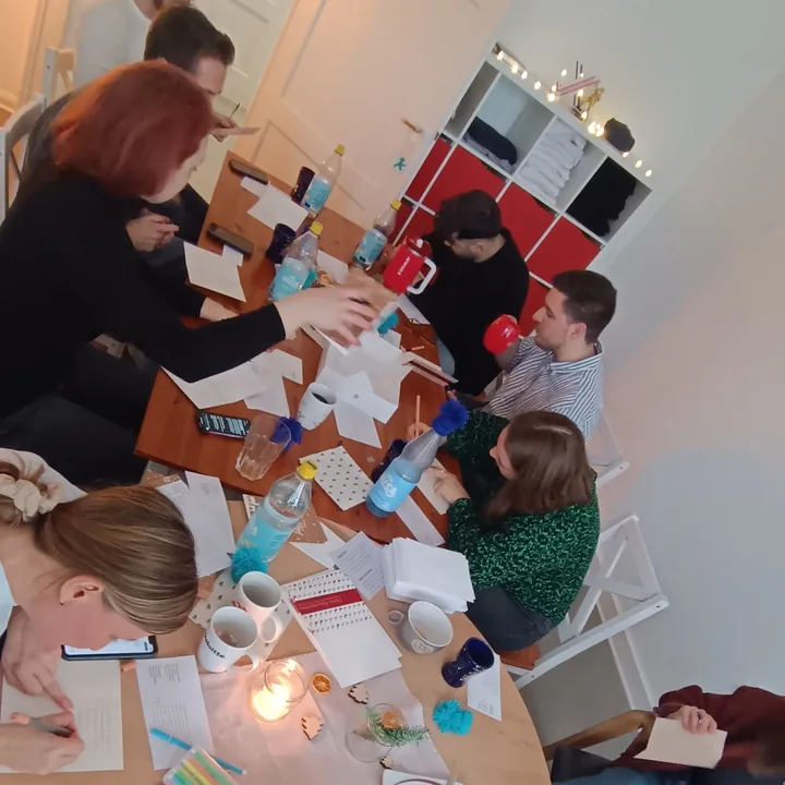 Das Team schreibt an einem runden Tisch Weihnachtskarten an einsame Menschen, Dezember 2025